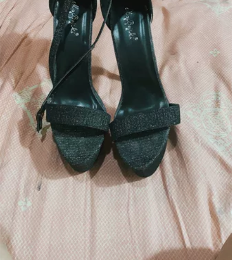 出黑色亮片高跟凉鞋，款式为鱼嘴鞋，鞋头露趾...